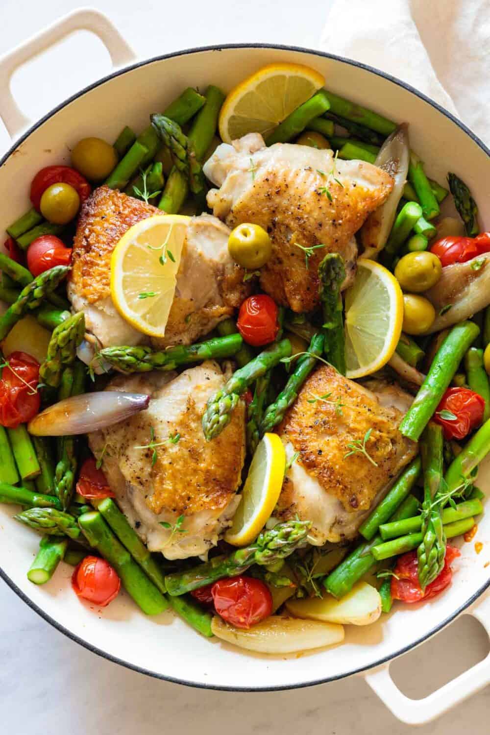 Closeup shot of texture of chicken and vegetables in a big white pan.