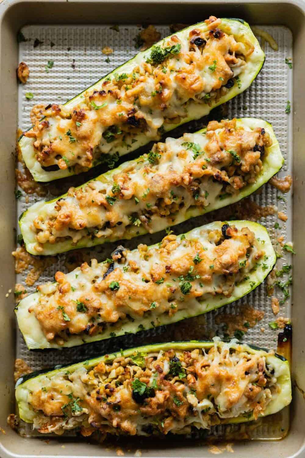 Four stuffed zucchini boats on a baking sheet.
